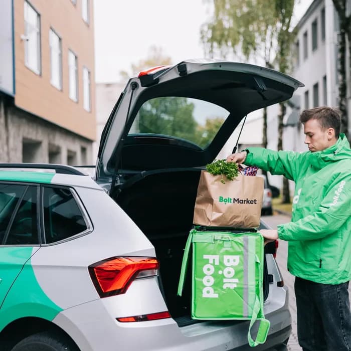 Kuriér Bolt Food nakladá objednávku do auta